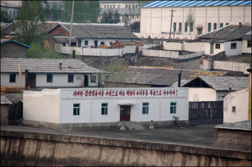 북한 양강도 중부 압록강 연안에 있는 혜산시의 일부로, 건물 외벽에 구호가 적혀 있다.