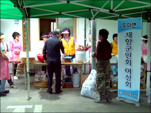  재향군인회여성회가 어르신들에게 대접할 음식을 준비하고 있다. 뒷건물이 새옷으로 갈아입은 마을회관.
