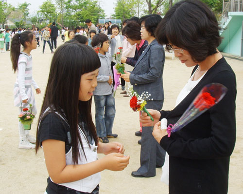  성북초등학교 학생들이 선생님들에게 감사하는 마음을 담은 빨간 카네이션 꽃을 가슴에 달아주고 있다.