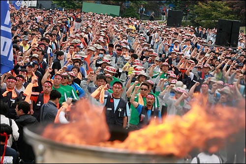 22일 오후 경기도 평택 쌍용자동차 공장에서 열린 '정리해고 분쇄 금속노동자 결의대회'에서 총파업에 돌입한 쌍용자동차 노동자를 비롯한 민주노총 금속노조 조합원들이 '총파업 성화'에 불을 붙인 뒤 구호를 외치고 있다.