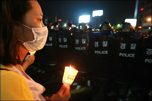 24일 밤 고 노무현 전 대통령 분향소가 마련된 서울 덕수궁앞에서 촛불을 든 한 추모객이 서울광장을 원천봉쇄한 경찰들앞에 서 있다.