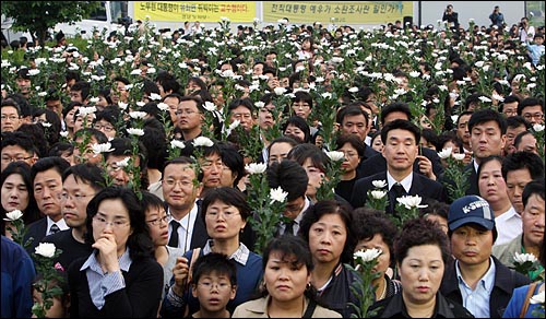 경남 김해시 진영읍 봉하마을 노무현 전 대통령의 빈소를 찾은 조문객들이 24일 오후 국화꽃을 들고 분향소앞에 줄지어 서 있다.
