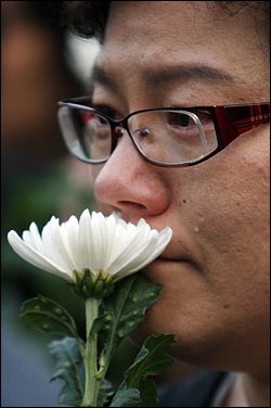 24일 경남 김해시 진영읍 봉하마을 노무현 전 대통령의 빈소를 찾은 한 조문객이 국화꽃을 들고 눈물을 흘리고 있다.