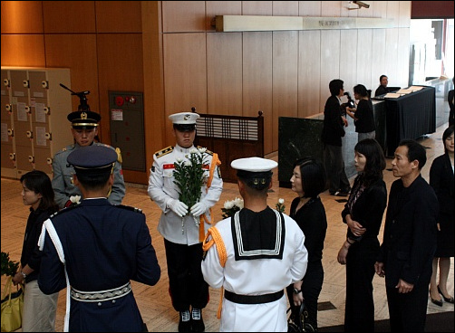 해군들이 조문객들에게 국화를 나눠주고 있다.