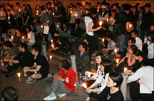 노무현 전 대통령을 추모하기 위해 25일 밤 서울 덕수궁 대한문 앞 분향소를 찾은 시민들이 촛불을 들고 노 전 대통령의 생전 모습을 담은 영상을 보고 있다.