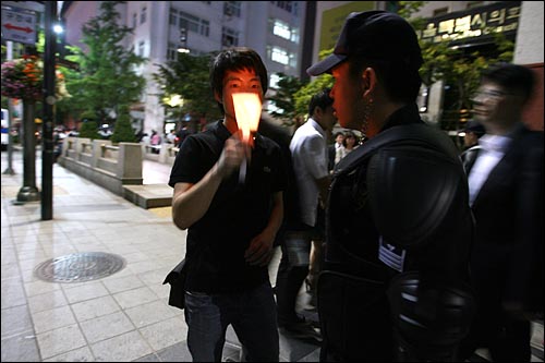 26일 밤 서울 덕수궁앞에 마련된 고 노무현 전 대통령 분향소에서 조문을 마친 한 시민이 촛불을 든 채 돌아가려 하자 경찰이 가로막고 있다.