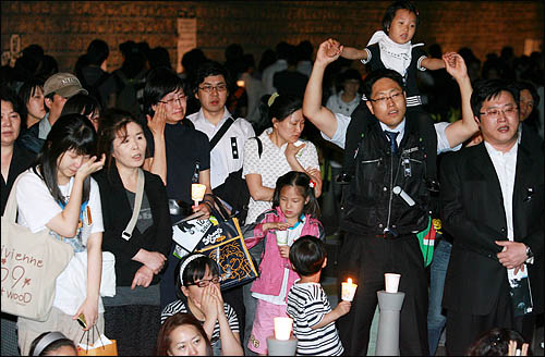 노무현 전 대통령을 추모하기 위해 27일 저녁 서울 덕수궁 돌담길에 모인 시민들이 시민악단 연주에 맞춰 '함께 가지 우리 이 길을' 노래를 부르며 흐느끼고 있다.