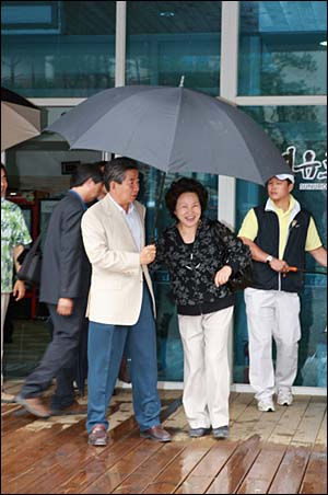 2008년 7월 24일. 강원도 정선 하이원 리조트 방문시 비가 내리는 식당 앞에서 권 여사가 우산을 따로 펼치려 하자 다정하게 자신의 우산으로 끌어당기는 모습