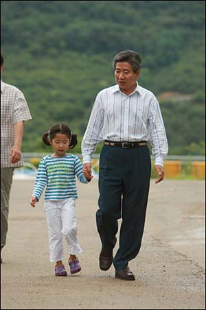 2008년 8월 16일. 사저 옆 잔디밭으로 자원봉사자들을 만나기 위해 손녀와 같이 걸어가는 모습