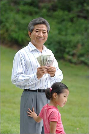 2008년 8월 17일. 사저 옆 잔디밭에서 한 자원봉사자가 "희망돼지를 정리하다 나온 돈"이라며 건넨 돈을 받아 펼쳐 보이며 지난 대선당시를 회고하듯 밝은 표정을 보이는 대통령님. 앞은 손녀 서은양