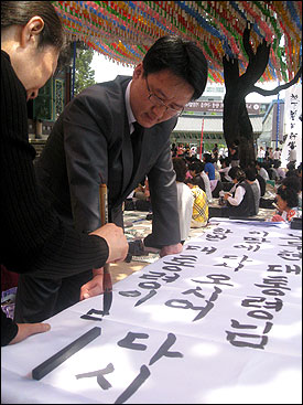  28일 오전 서울 종로구 견지동 조계사에서 한 불교신자가 노 전 대통령 노제에 쓰일 만장을 쓰고 있다.