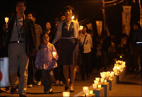 노무현 전 대통령 발인을 하루 앞둔 28일 밤 경남 김해 봉하마을 분향소를 찾은 추모객들이 애도의 뜻을 표하며 촛불을 들고 지나가고 있다.