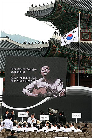 고 노무현 전 대통령 영결식이 열리는 29일 오전 서울 경복궁에 조기가 내걸린 가운데 고인의 생전 에 기타를 치며 '상록수' 노래를 부르는 영상이 나오고 있다.