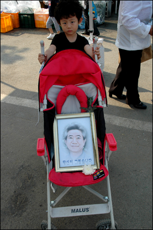 봉하마을을 찾은 한 아이가 유모차에 노무현 전 대통령의 얼굴이 담긴 액자를 싣고 있다.