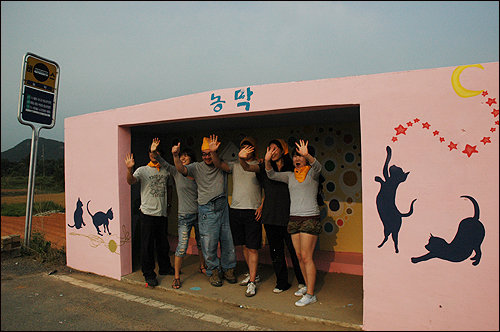  농막마을 버스정류장 무료벽화작업을 마친 '좋은세상만들기' 회원들이 손을 흔들며 기뻐하고 있다.