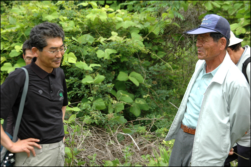  진실화해를위한과거사정리위원회가 '한국전쟁 전후 진주형무소 재소자와 진주지역 국민보도연맹 사건' 관련 희생자의 유해를 발굴하기로 한 가운데, 10일 오후 진주명석면사무소에서는 개토제가 열렸고 이후 유족회는 명석면 용산리 등 매장지를 둘러보았다. 사진은 명석면 용산리 매장지에서 이상길 경남대 교수(왼쪽)와 이야기를 나누고 있는 진주유족회 김판규씨의 모습.