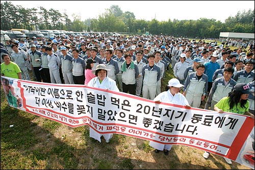 쌍용자동차 공장 주변에 사측 직원들이 공장진입을 시도하기 위해 집결한 가운데 농성중인 노동자들의 가족이 현수막을 들고 공장진입을 가로막고 있다.