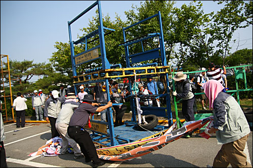  26일 오후 쌍용차 평택 공장 내로 진입한 정리해고 비대상자 1000여명이 파업 노조원이 공장 울타리에 쌓아놓은 기자재를 치우고 있다.