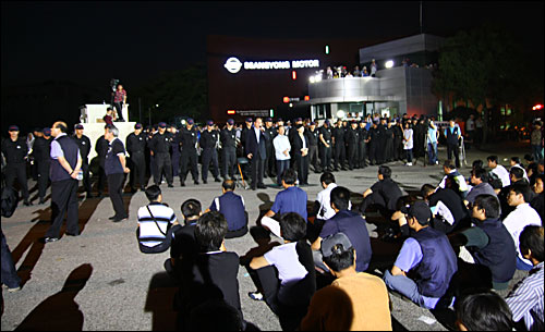 26일 밤 쌍용차 평택 공장 정문 앞에서 파업 노조원 가족과 민주노동당·민주노총·시민사회단체 관계자 100여 명이 사측의 공장 진입을 규탄하는 집회를 열고 있다. 