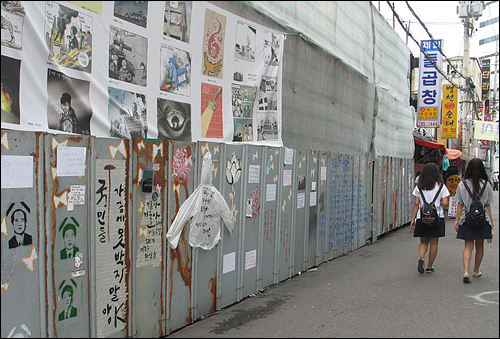 13일 오후 용산참사가 일어난 남일당 건물 맞은편 골목으로 고등학생들이 지나가고 있다. 철거용 임시벽에는 희생자들의 영정 사진 등 다양한 그림이 그려져있다.