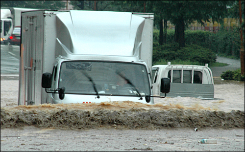 마산 봉암교 입구 3거리 도로가 16일 내린 비로 침수되어 트럭이 물에 잠겨 있다.
