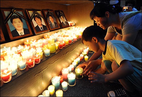 한 어린이와 부모가 희생자 영장 앞에 고인의 넋을 위로하며 촛불을 놓고 있다.