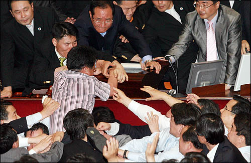 미디어법 강행처리를 저지하기 위해 2009년 7월 22일 당시, 국회 본회의장에 입장한 강기정 민주당 의원이 이윤성 부의장이 앉아 있는 의장석쪽으로 뛰어올라 거세게 항의하자 김효재 한나라당 의원이 완력으로 밀어내고 있다.