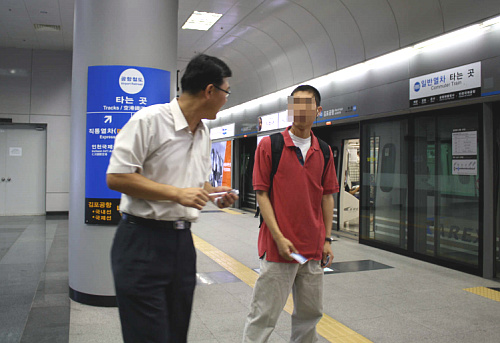 김포공항역으로 9호선을 타고 온 공항철도 정기권 승객이 환승하는 방법을 역무원에게 묻고 있다.