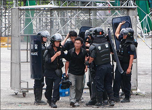 KBS 카메라 기자와 오디오맨이 점거농성을 벌이고 있는 쌍용차 노조원들을 취재하고 나오다가 경찰들에게 붙잡혀 연행되고 있다.