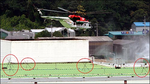 경찰특공대를 태운 헬기가 공장옥상에서 안전한 착륙장소를 찾고 있다. 공장옥상에는 헬기착륙을 막기위한 방해물(빨간 원)이 설치되어 있다.