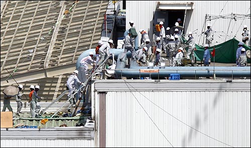 경찰특공대가 차체2팀 공장 옥상에 진입하는 가운데 농성노동자들이 사다리를 타고 도장공장 옥상으로 후퇴하고 있다.