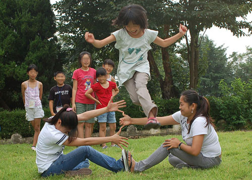더 높이 뛸 수 있어요! 필리핀 전통놀이인 장애물 뛰어넘기를 즐기는 선생님과 아이들