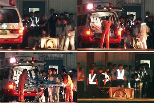 6일 밤 다리를 다친 한 부상자가 리어카에 실려 도장공장에서 나온 뒤 구급차에 오르고 있다.