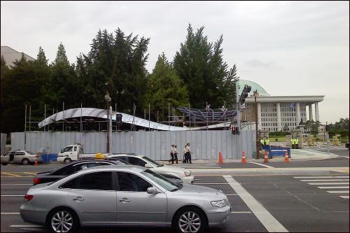 국회 건너편에서 본 국회의사당역 국회정문쪽 출입구 지붕(공사 중)과 국회의사당 돔형 지붕.
