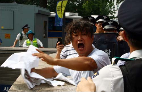 김대중 전 대통령 서거 소식을 알리는 한 시민이 경찰에 의해 제지당하고 종이까지 뺏아기자 울분을 터트리고 있다.