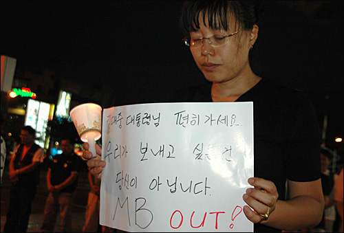 18일 저녁 창원 정우상가 앞에서 열린 '용산참사 해결을 위한 촛불문화제'에 참석한 한 시민이 종이피켓과 촛불을 들고 묵념하고 있다.