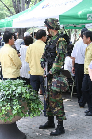 한 군 헌병대원이 경계근무를 서고 있다. 그 뒤쪽에는 대구시장을 포함한 훈련을 참관하는 인사들이 앉아있는 참관대가 위치해 있다.