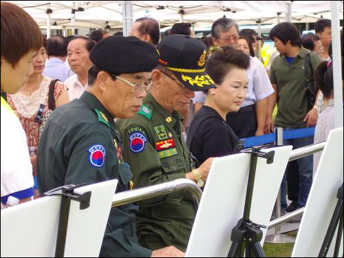 군복 차림의 베트남 참전 유공자 김기영씨(오른쪽)가 분향 순서를 기다리며 김 전 대통령 생전의 사진을 보고 있다.