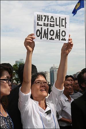 북측 특사 조의방문단이 21일 오후 여의도 국회에 마련된 고 김대중 전 대통령 국장 빈소를 조문한 가운데 이를 지켜보던 한 시민 환영하는 손피켓을 들고 있다.
