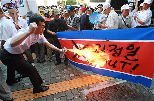 21일 오후 조문단 숙소앞에서 반핵반김국민협의회, 대한민국어버이연합 등 보수단체 회원들이 '김정일 OUT'라고 적힌 인공기에 불을 붙이고 있다.