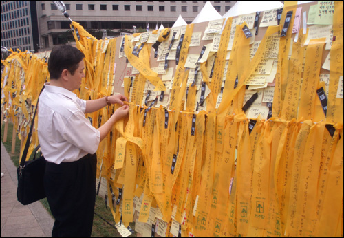'김대중 전 대통령 추모의 벽'에 추모 리본을 달고 있는 시민.