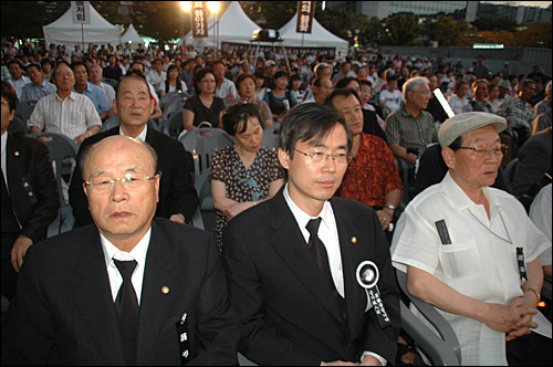 22일 저녁 부산역 광장에서 열린 고 김대중 전 대통령 추모문화제에 조경태 의원(가운데)이 참석해 시민들과 함께 의자에 앉아 있다.