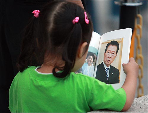고 김대중 전 대통령 국장 빈소에서 한 어린이가 김 전 대통령의 마지막 일기 모음집 <인생은 아름답고 역사는 발전한다>속 사진을 보고 있다.