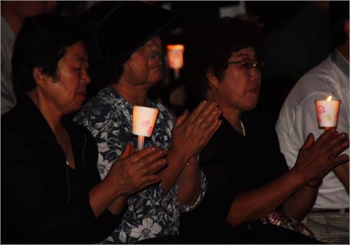 22일 밤 서대전시민공원에서 열린 '고 김대중 대통령 서거 대전시민 추모문화제'에 참석한 시민들이 고인의 명복을 빌며 합장을 하고 있다.
