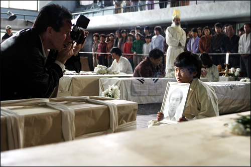 제 아버지를 찾아주세요! 계엄군의 총칼에 희생당한 아버지의 영정사진을 들고 있는 어린아이의 모습을 외신기자가 촬영하고 있다.