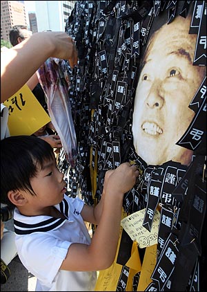 23일 오후 고 김대중 전 대통령 국장 영결식이 국회에서 열리는 가운데 서울광장 분향소에 마련된 추모의 벽에 한 어린이가 근조리본을 달고 있다.