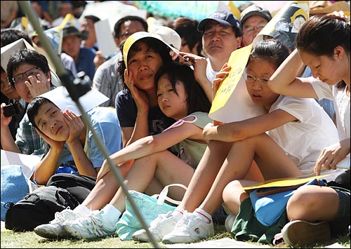 뜨거운 햇볕에도 불구하고 서울광장에 마련된 분향소에 많은 추모객들이 모여 앉아 영결식 생중계를 시청하고 있다.