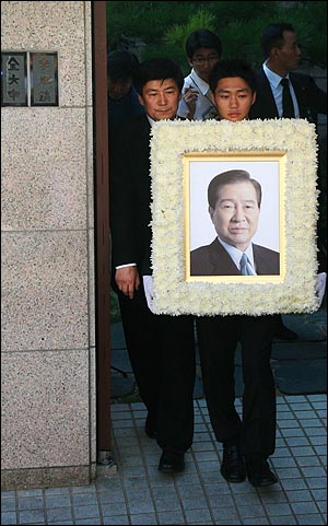 고인의 손자가 영정사진을 들고 김 전 대통령 부부의 문패가 함께 걸려 있는 사저를 둘러본 뒤 나오고 있다.