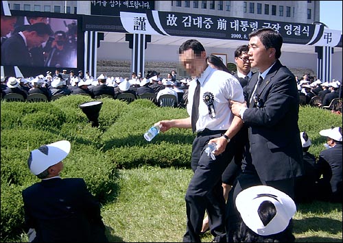 23일 오후 여의도 국회의사당 앞마당에서 엄수된 고 김대중 전 대통령 국장 영결식에서 이명박 대통령이 헌화를 하려는 순간 '위선자'라고 소리치던 한 30대 남성이 경호원들에 의해 끌려나가고 있다. 