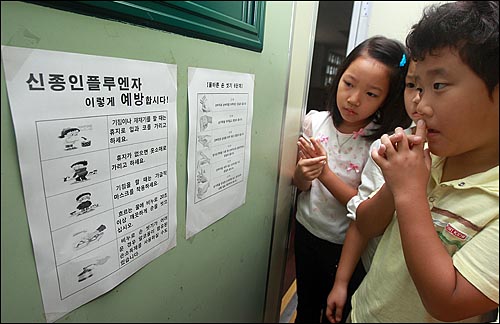 27일 오전 서울 신용산초등학교에서 학생들이 교실 벽에 붙여진 신종 인플루엔자 예방 안내문을 보고 있다.